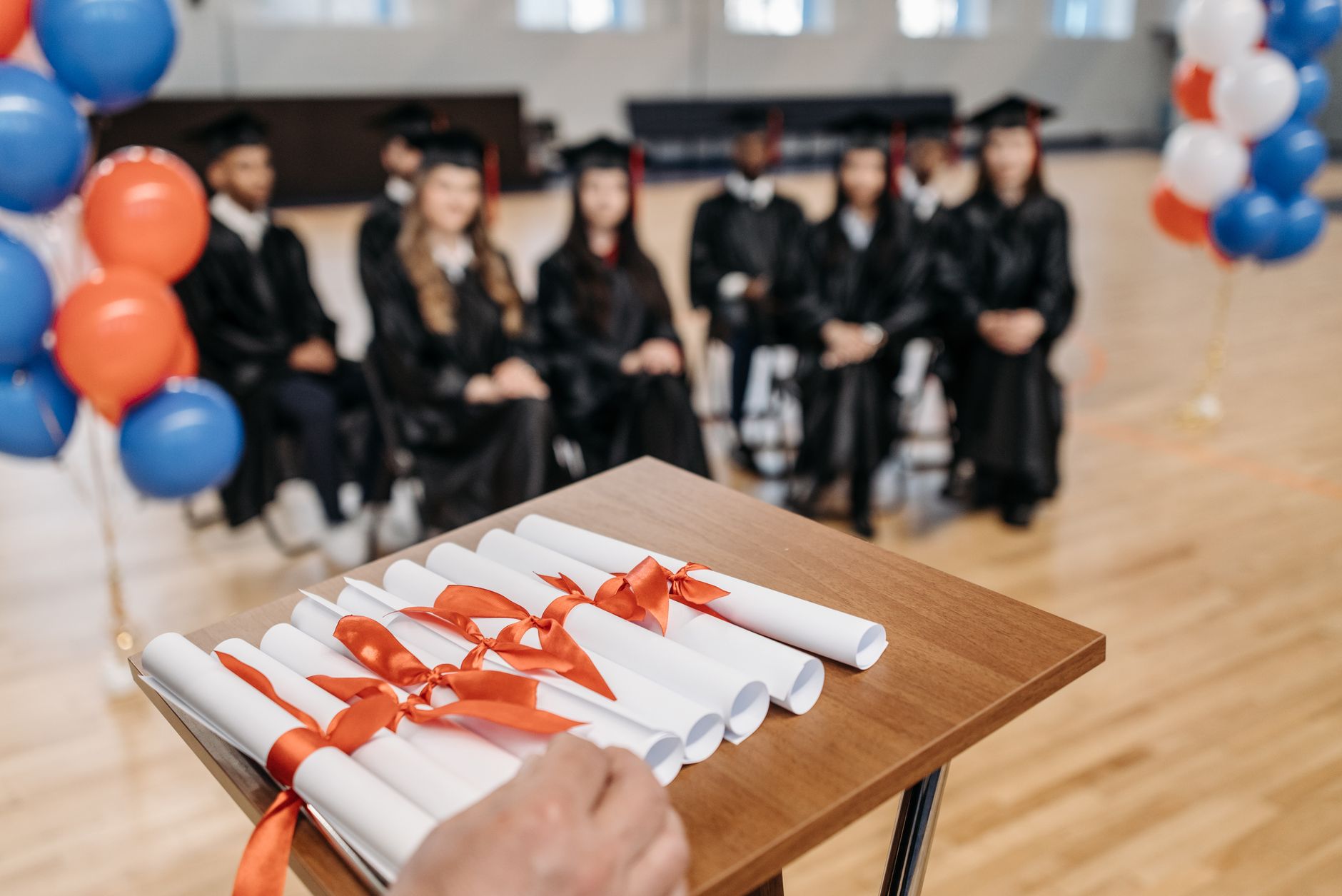 A graduation cap and rolled diploma resting on a table